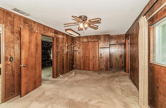 spare room featuring ceiling fan, wooden walls, and light colored carpet