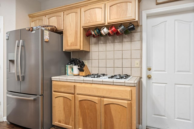 kitchen with tile counters, decorative backsplash, white gas cooktop, and stainless steel fridge with ice dispenser