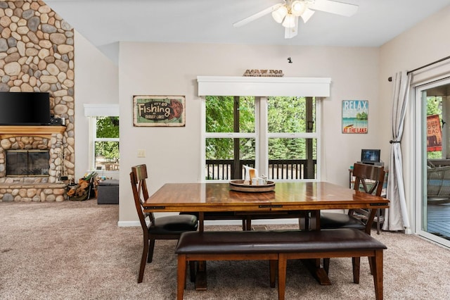 carpeted dining area featuring ceiling fan and a fireplace