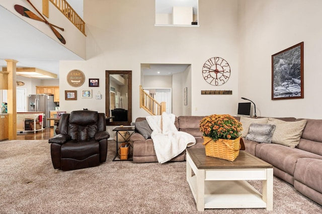 carpeted living room featuring a towering ceiling and ornate columns