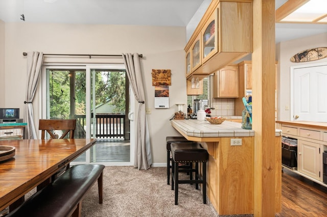 kitchen featuring dark hardwood / wood-style floors, tasteful backsplash, a kitchen bar, tile countertops, and black oven