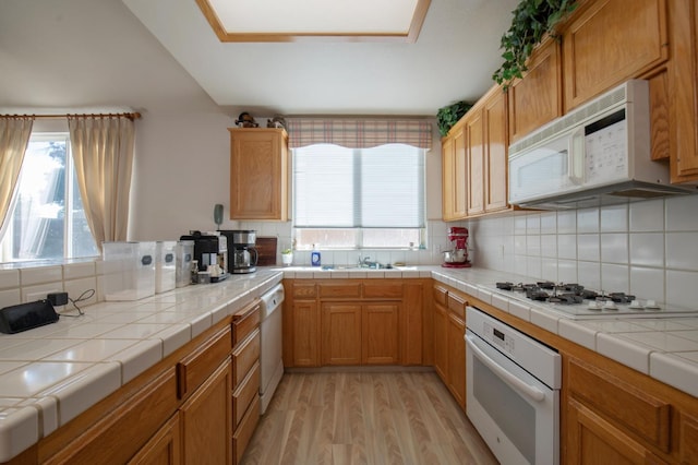 kitchen featuring light hardwood / wood-style floors, white appliances, tile countertops, and backsplash