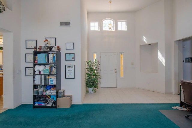 foyer featuring carpet floors and a towering ceiling