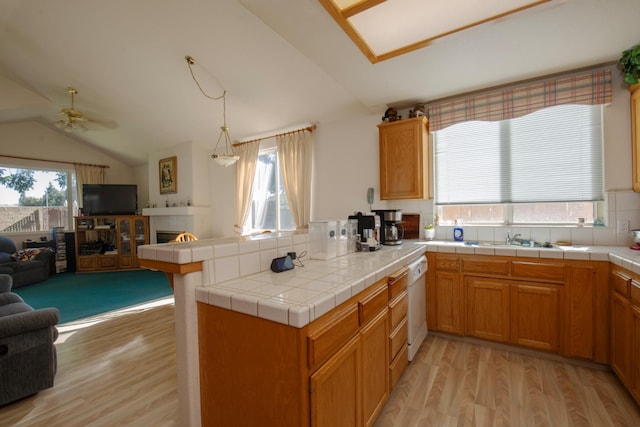 kitchen featuring plenty of natural light, kitchen peninsula, vaulted ceiling, and tile counters