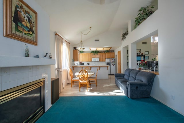 living room with a fireplace, light colored carpet, and high vaulted ceiling