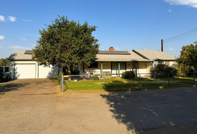 single story home featuring solar panels, a chimney, a front lawn, a garage, and a fenced front yard