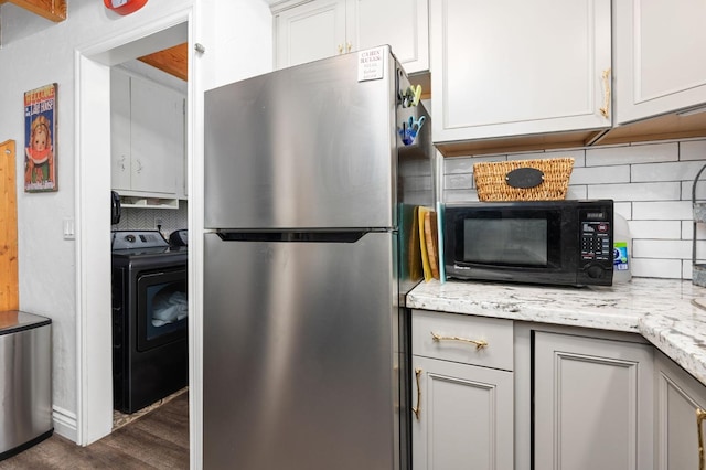 kitchen with dark hardwood / wood-style flooring, stainless steel refrigerator, light stone countertops, and tasteful backsplash