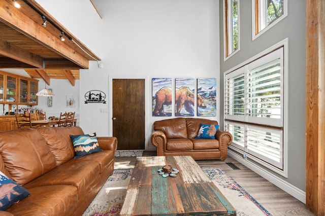 living room with a towering ceiling, beamed ceiling, and hardwood / wood-style flooring