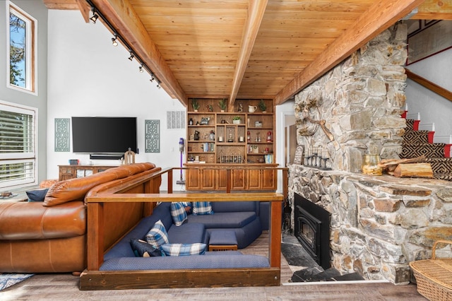 living room featuring wood ceiling, beamed ceiling, and a stone fireplace