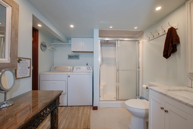 bathroom featuring a shower with door, vanity, independent washer and dryer, and toilet