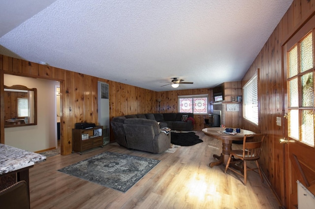 living room with ceiling fan, a textured ceiling, and light hardwood / wood-style flooring