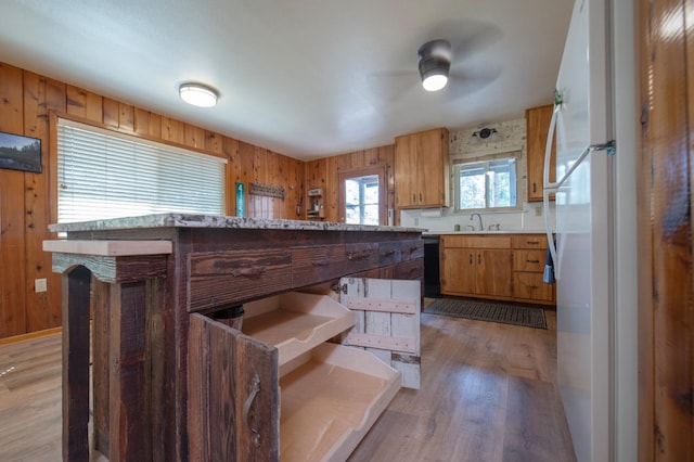 kitchen featuring wood walls, sink, white fridge, light hardwood / wood-style floors, and ceiling fan