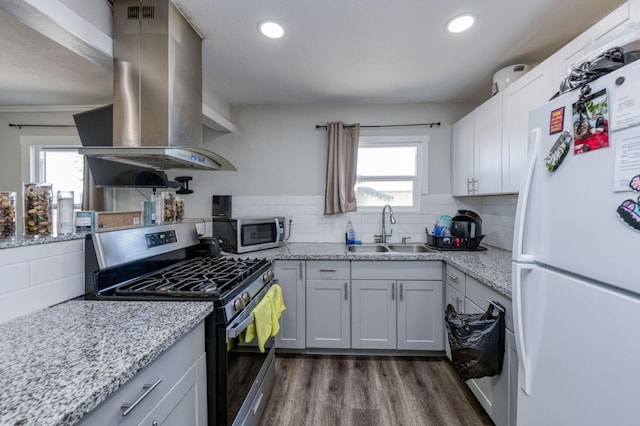 kitchen with backsplash, island exhaust hood, sink, dark wood-type flooring, and appliances with stainless steel finishes