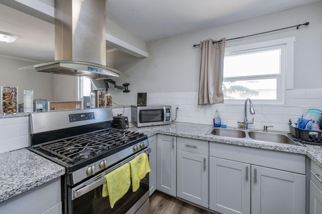 kitchen with appliances with stainless steel finishes, sink, island exhaust hood, dark wood-type flooring, and decorative backsplash