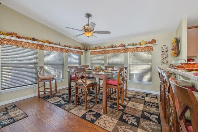 dining area with ceiling fan, dark hardwood / wood-style flooring, and vaulted ceiling