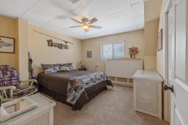 carpeted bedroom with ceiling fan and a drop ceiling