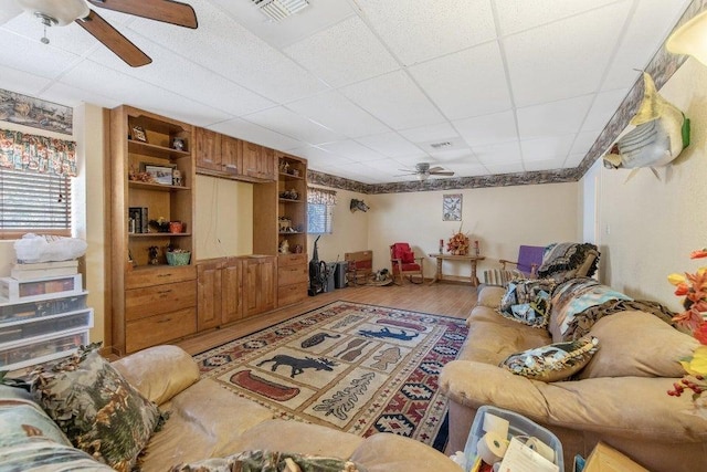 living room with visible vents, wood finished floors, a drop ceiling, and a ceiling fan