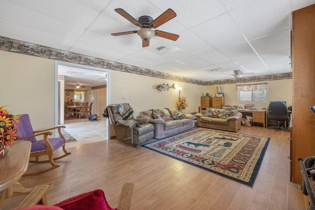 living room featuring a drop ceiling, ceiling fan, and light hardwood / wood-style floors