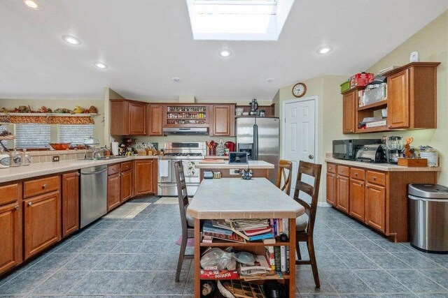 kitchen with brown cabinetry, under cabinet range hood, and appliances with stainless steel finishes