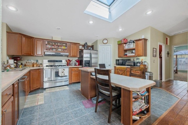kitchen featuring appliances with stainless steel finishes, under cabinet range hood, a sink, open shelves, and a center island
