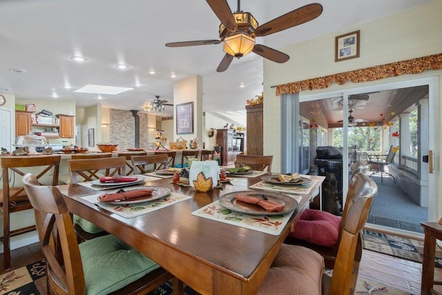 dining space with ceiling fan and a skylight