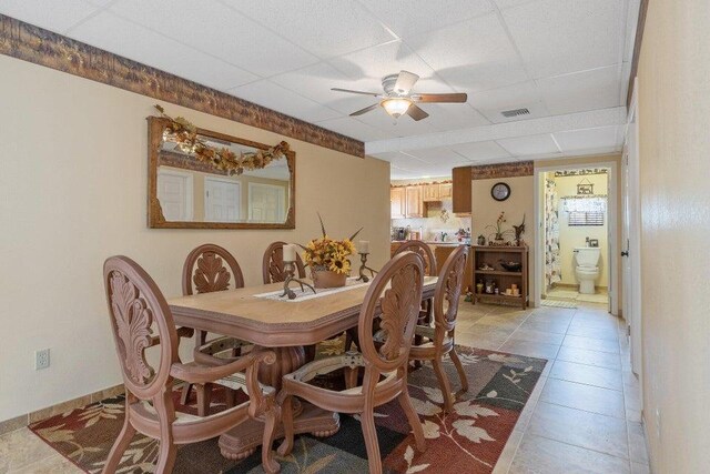 tiled dining area featuring ceiling fan and a drop ceiling