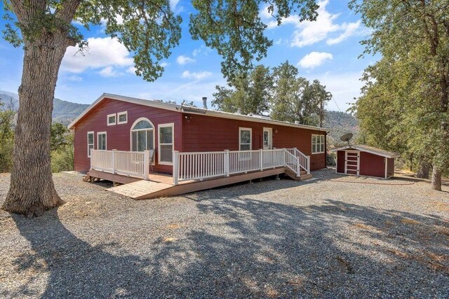 view of front of property with a deck with mountain view and a shed