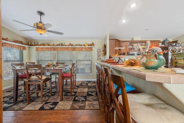 dining space with dark wood-type flooring, ceiling fan, and bar