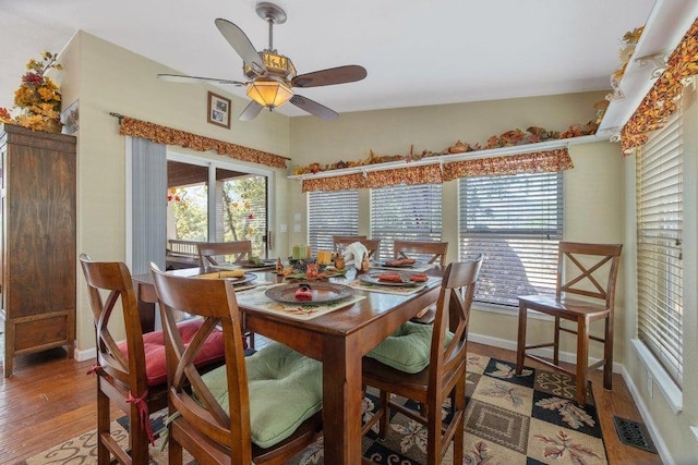 dining space featuring baseboards, visible vents, wood finished floors, and a ceiling fan
