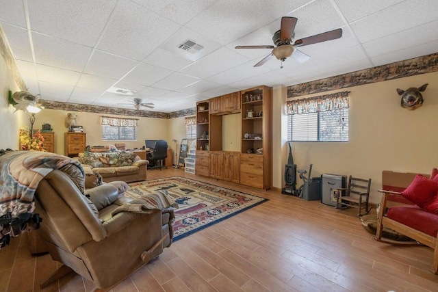 living room with ceiling fan, hardwood / wood-style flooring, and a drop ceiling