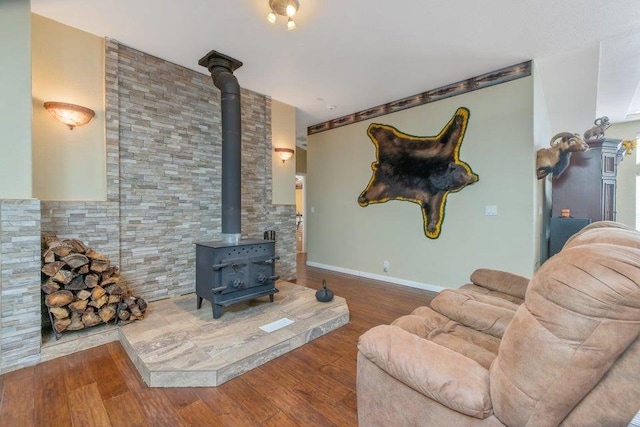 living area featuring baseboards, wood finished floors, and a wood stove