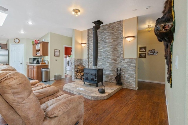 living room with hardwood / wood-style floors, a wood stove, and washer / clothes dryer