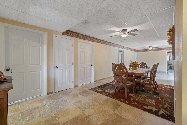 dining space featuring stone finish floor, ceiling fan, visible vents, and a drop ceiling