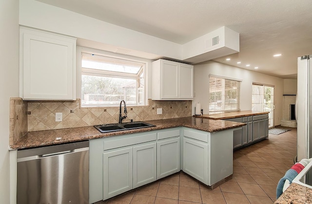 kitchen with sink, white cabinets, tasteful backsplash, kitchen peninsula, and stainless steel dishwasher