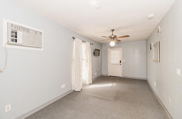 empty room with an AC wall unit, ceiling fan, a textured ceiling, and carpet flooring