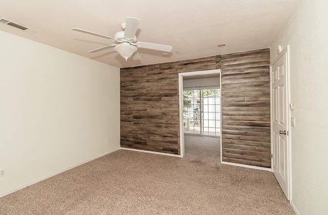 spare room featuring ceiling fan, log walls, a textured ceiling, and carpet flooring