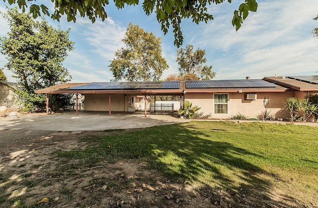 rear view of house with solar panels, a patio area, and a lawn