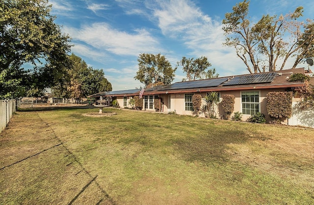 rear view of house featuring solar panels and a lawn