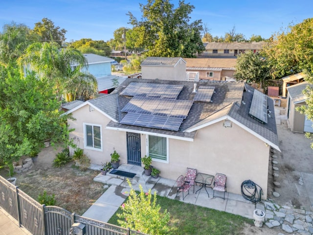 view of front of home featuring solar panels, a storage shed, and a patio area