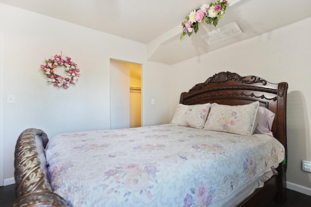 bedroom featuring a spacious closet and dark hardwood / wood-style flooring