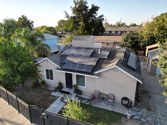 view of front facade with a shed, solar panels, and a patio area