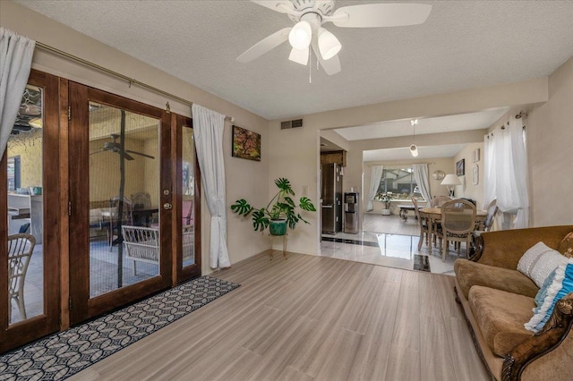 living room with a textured ceiling, light hardwood / wood-style flooring, and ceiling fan