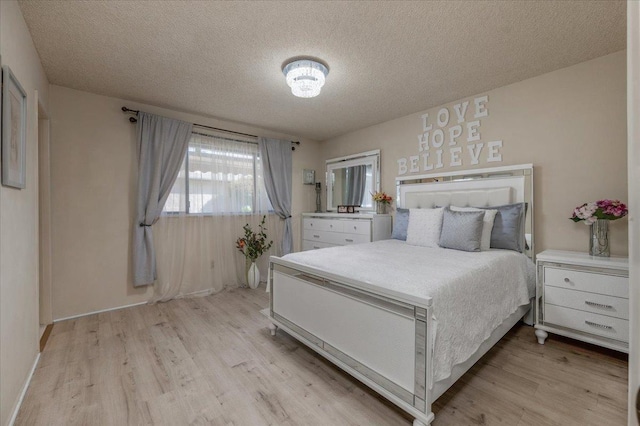 bedroom with a textured ceiling and light hardwood / wood-style flooring