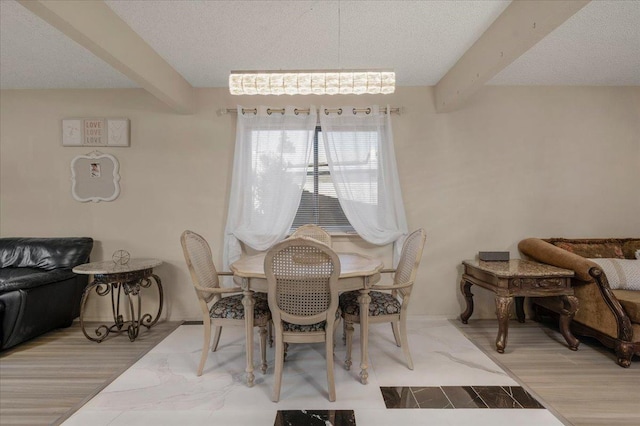 dining space with a textured ceiling, hardwood / wood-style floors, and beamed ceiling