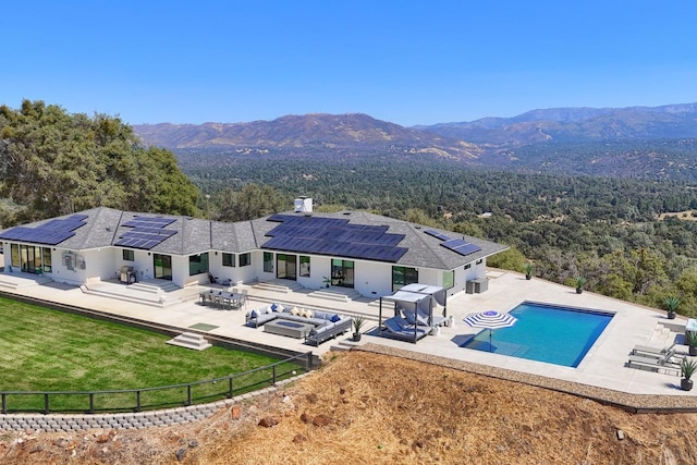 exterior space with a fenced in pool, solar panels, a mountain view, and a patio