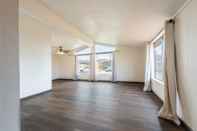 spare room featuring dark wood-style floors, a textured ceiling, baseboards, and vaulted ceiling with beams