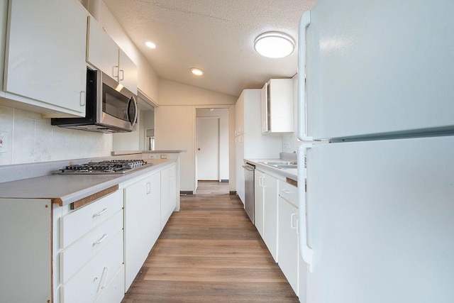 kitchen with light countertops, appliances with stainless steel finishes, white cabinets, a textured ceiling, and light wood-type flooring