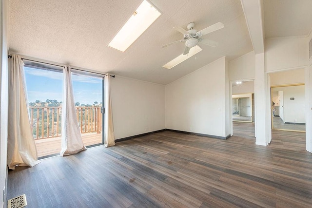 interior space featuring baseboards, visible vents, lofted ceiling with skylight, dark wood-type flooring, and a textured ceiling