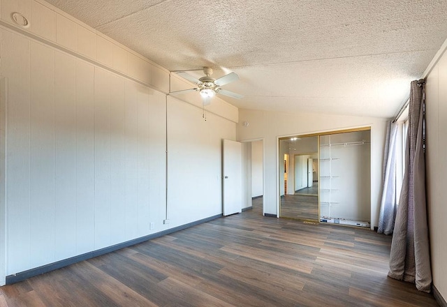 unfurnished bedroom with a textured ceiling, a ceiling fan, vaulted ceiling, and dark wood-style flooring