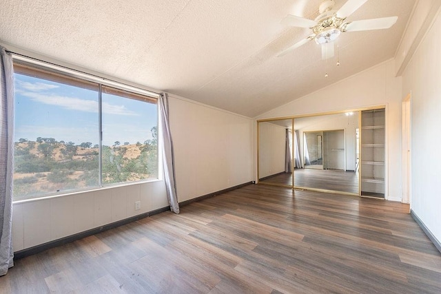 spare room featuring dark wood-style floors, lofted ceiling, ceiling fan, and a textured ceiling